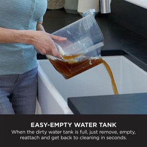 Person in light blue cardigan emptying brown dirty water from transparent tank of Shark CarpetXpert carpet cleaner into white basin, demonstrating easy-empty water tank feature