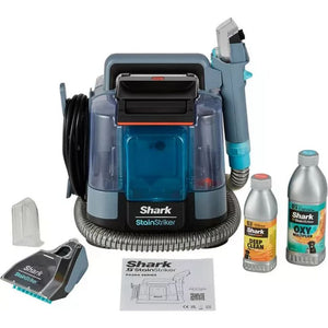 Shark StainStriker portable carpet cleaner in Nordic blue and grey with turquoise accents, displayed with included accessories including cleaning solution bottles, handheld attachment, power cord, and instruction manual on white background