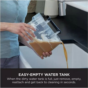 Person in light blue shirt emptying tan-colored dirty water from transparent tank of Shark portable carpet cleaner into white sink, demonstrating easy-empty water tank feature