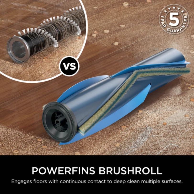 Comparison diagram of Shark PowerPro vacuum brushroll technology showing traditional spiral brush versus blue PowerFins brushroll design engaging carpet and hard floors with 5 year guarantee badge