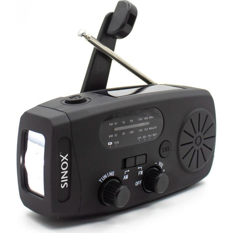 Black Sinox compact emergency radio with hand crank dynamo, featuring FM/AM tuning dial, LED flashlight, SOS button, and telescopic antenna on white background
