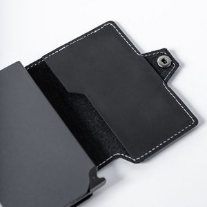 Wallet Junkie Pro Slim midnight black leather cardholder with white stitching and snap closure, holding multiple cards, displayed open on white background