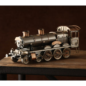 Detailed metal steam locomotive ornament with copper and silver-toned components featuring a boiler, smokestack, cabin, and four decorative wheels, displayed on a wooden base against a dark brown background