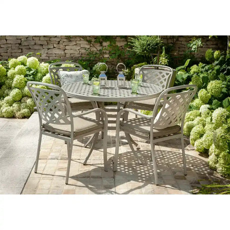 Hartman Berkeley 4 seater cast aluminium round garden furniture set with sage green lattice-back chairs, circular perforated table, cream cushions, set on stone patio surrounded by white flowering hydrangeas and green foliage