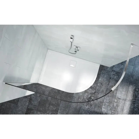 Modern white curved shower tray with chrome faucet mounted on grey tile bathroom floor and white walls