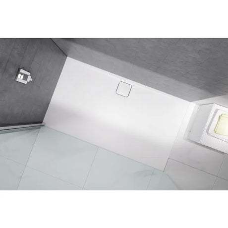 Merlyn Level25 white rectangular shower tray with 25mm height installed in modern bathroom with light grey tile flooring and concrete ceiling, featuring integrated drain cover