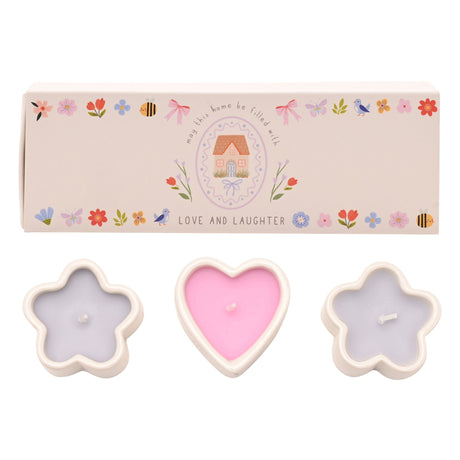 Set of three candles in star and heart shapes with a decorative box in the background.