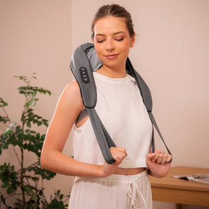 Woman using a neck and shoulder massager in a home setting