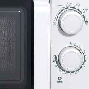 White Studio Collection 20 litre 700W manual microwave showing control panel with temperature dial, timer knob, and defrost settings, displayed next to microwave interior cavity