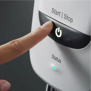 Hand pressing a 'Start/Stop' button on an appliance with a dark background