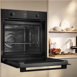 Neff N30 black built-in electric single oven with CircoTherm technology installed in cream kitchen cabinetry next to wooden shelves with white dishware and fresh vegetables