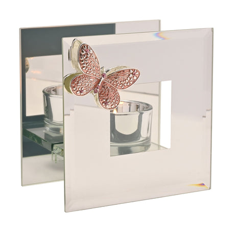 Pink decorative butterfly glass tea light holder with filigree detailing on clear glass panels featuring a cylindrical candle cup and mirrored backing