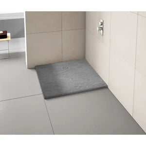 Modern bathroom shower enclosure featuring a dark grey slate-effect rectangular shower tray with integrated drain, cream tiled walls, chrome fixtures and light grey floor tiles