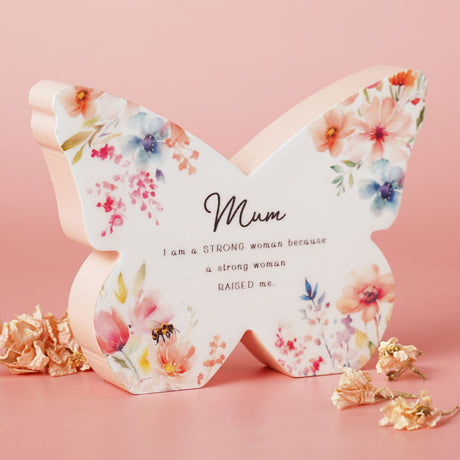 Butterfly-shaped decorative item with floral design and motivational quote on a pink background