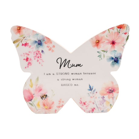 Butterfly-shaped decorative mantel plaque with watercolor floral design featuring pink, coral and blue flowers, yellow leaves and a bee, with black script text reading Mum and inspirational message about strong women