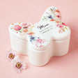Floral-patterned butterfly-shaped container with 'Mum, never forgot how loved you are' text on a pink background.