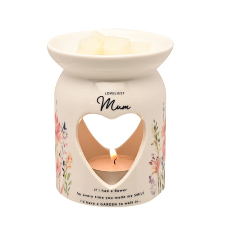 Cream ceramic wax melt burner with heart-shaped cutout, decorated with pink and purple wildflower illustrations, featuring "Loveliest Mum" text and sentimental message, with lit tealight candle visible inside and melting wax in top bowl