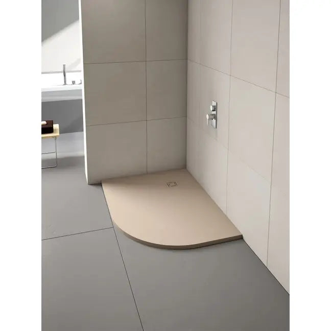 Merlyn Truestone curved offset quadrant shower tray in cream beige with dark trim installed in modern bathroom with large format wall tiles and chrome fixtures