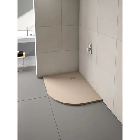 Merlyn Truestone curved offset quadrant shower tray in cream beige with dark trim installed in modern bathroom with large format wall tiles and chrome fixtures