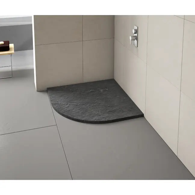 Modern bathroom shower tray installation showing black curved quadrant Merlyn Truestone tray with cream tile walls and grey floor in contemporary bathroom setting