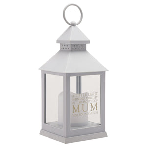 Grey memorial lantern with clear glass panels and white LED candle inside, featuring engraved text reading "A little light shining bright in memory of MUM miss you so much", topped with a conical roof and carrying handle