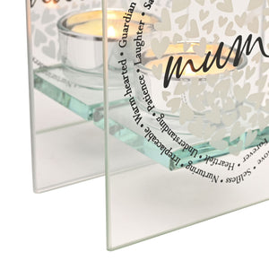 Clear glass tealight holder with heart pattern design featuring Mum sentiment in black script, accompanied by inspirational text including Heartfelt, Unbreakable, Treasure, Experience and Laughter, displayed with lit cream candle inside